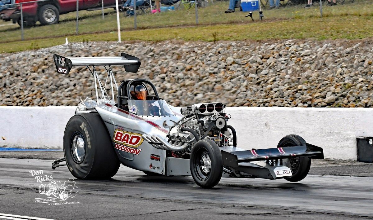 A drag race car is driving down a track.