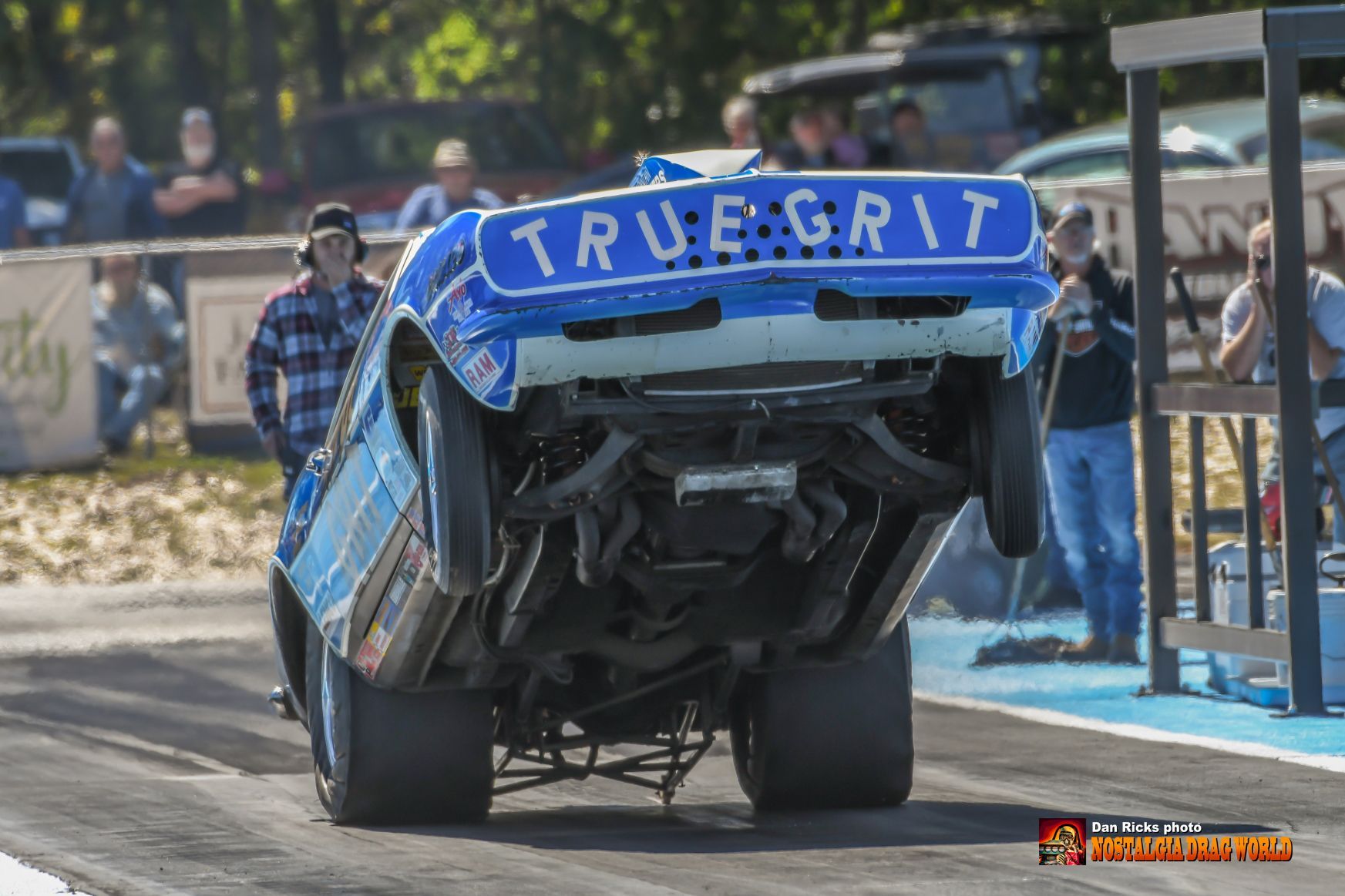 A blue and white race car is upside down on a race track.