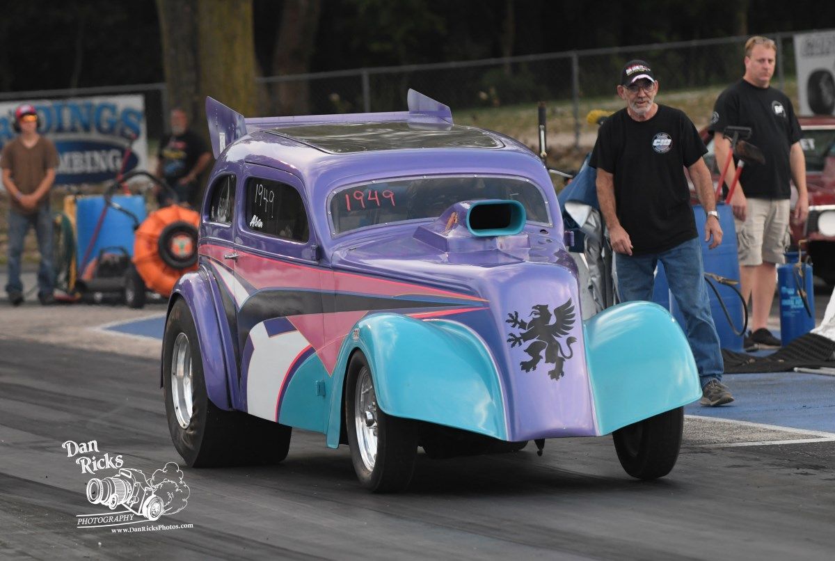 A purple and blue car is driving down a race track.