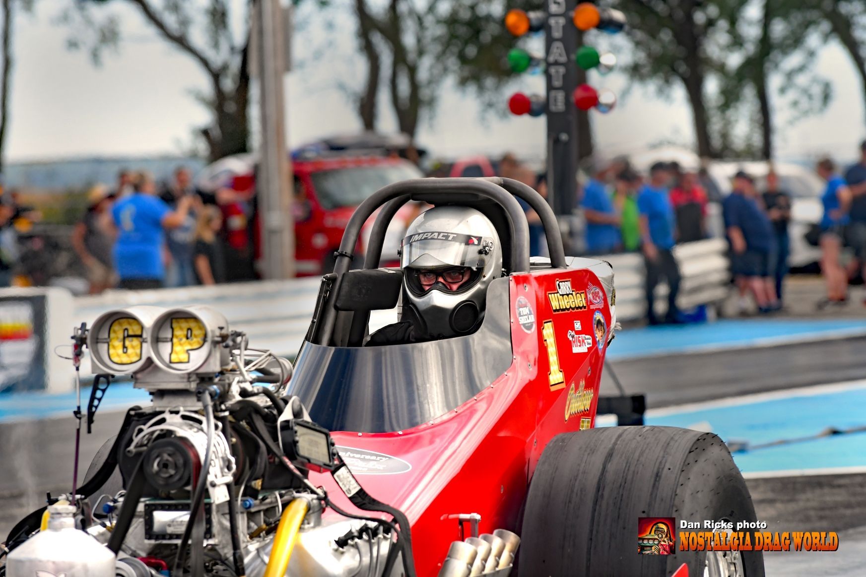 A man is sitting in a red race car on a track.