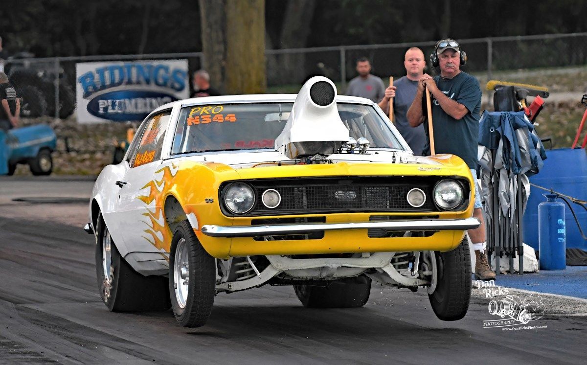 A yellow and white race car is driving down a track.