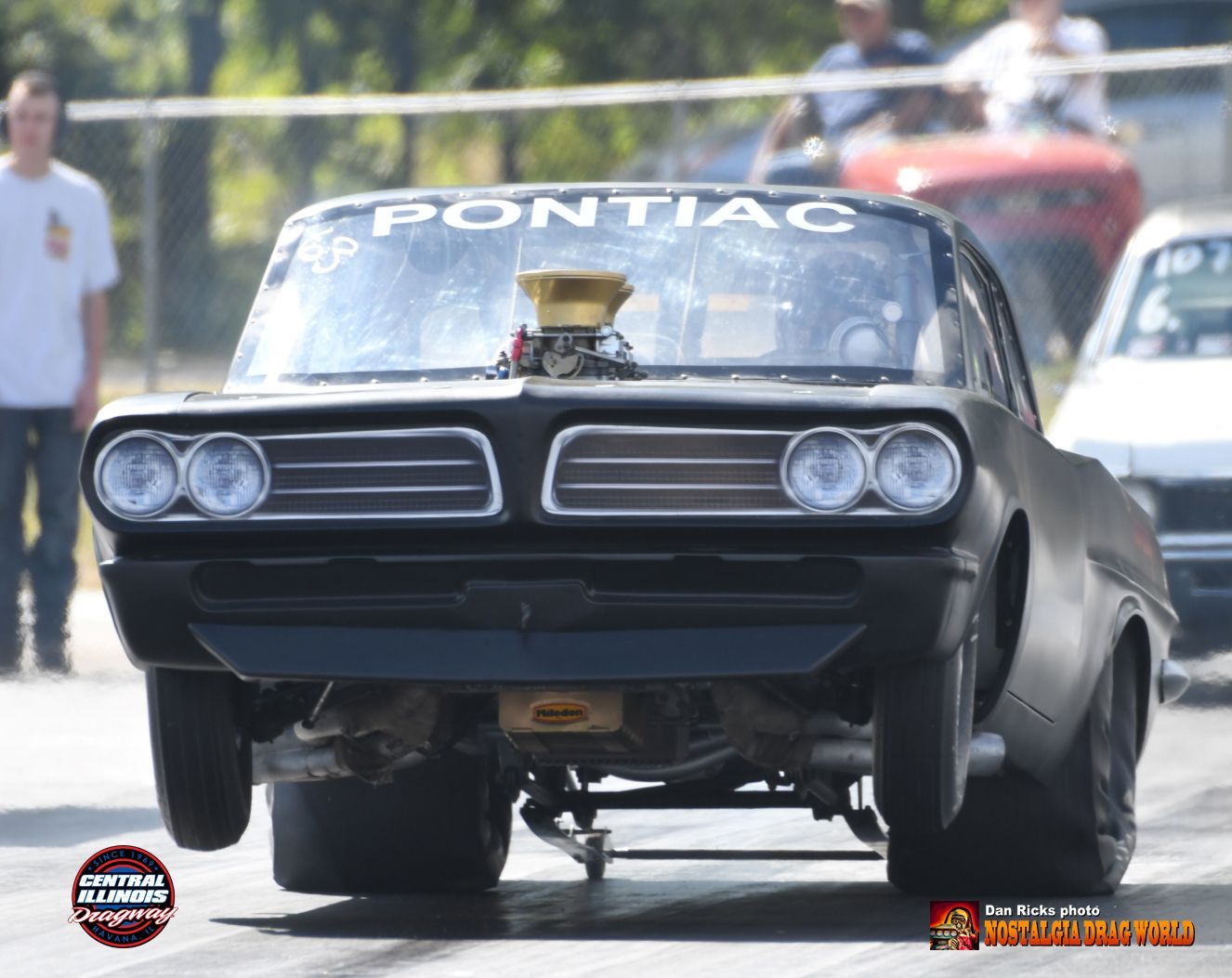 A black pontiac car is driving down a race track