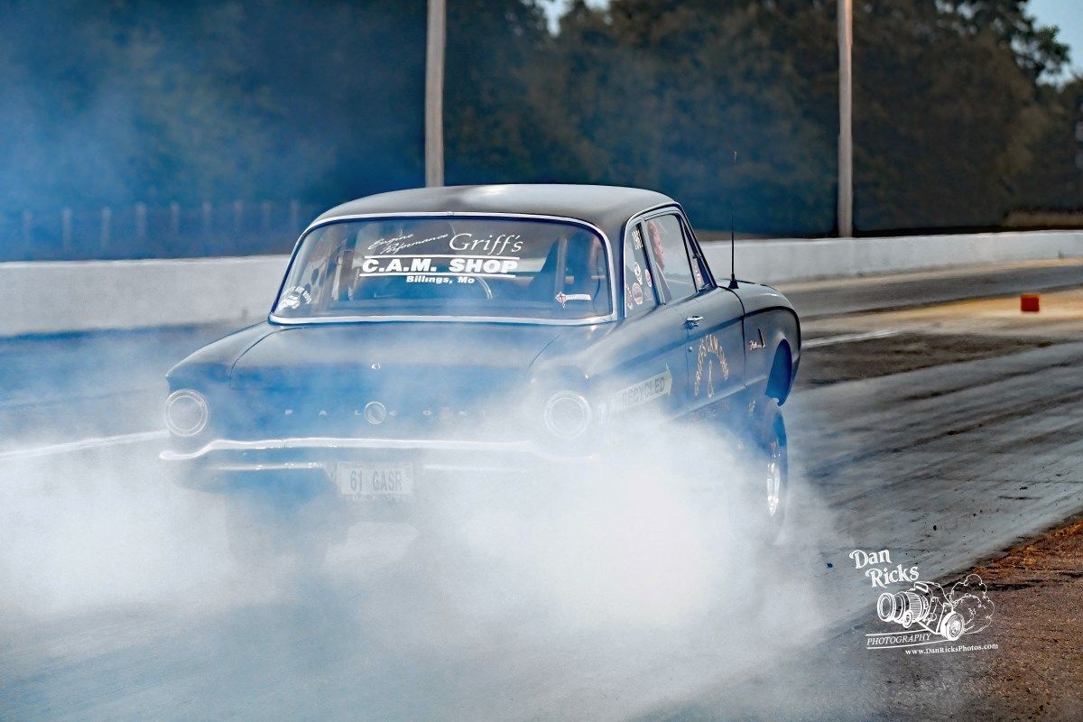 A car is doing a burnout on a race track.
