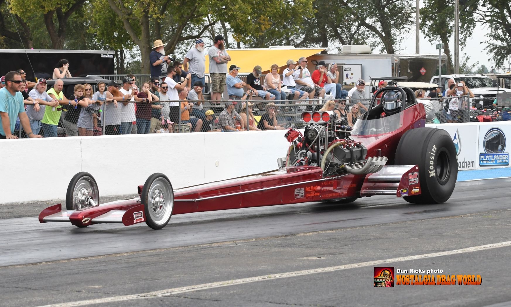 A red dragster is driving down a race track