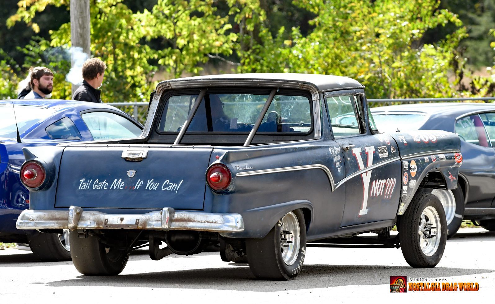 A blue truck with the word y on the back is parked in a parking lot.