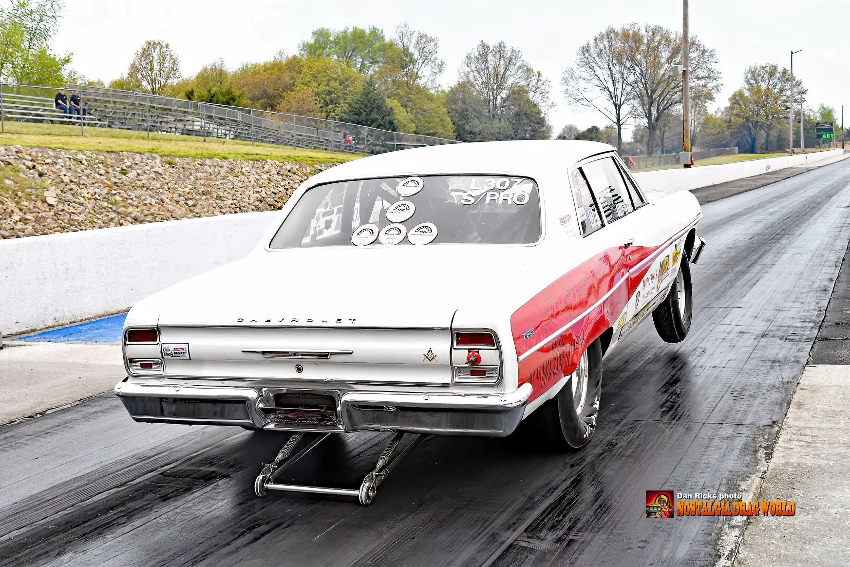 A red and white car is driving down a race track.