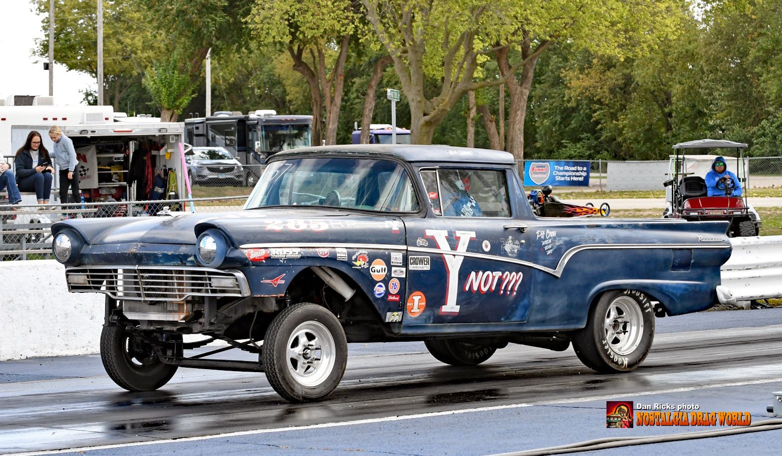 A blue truck with the word ny on the side is driving down a race track.