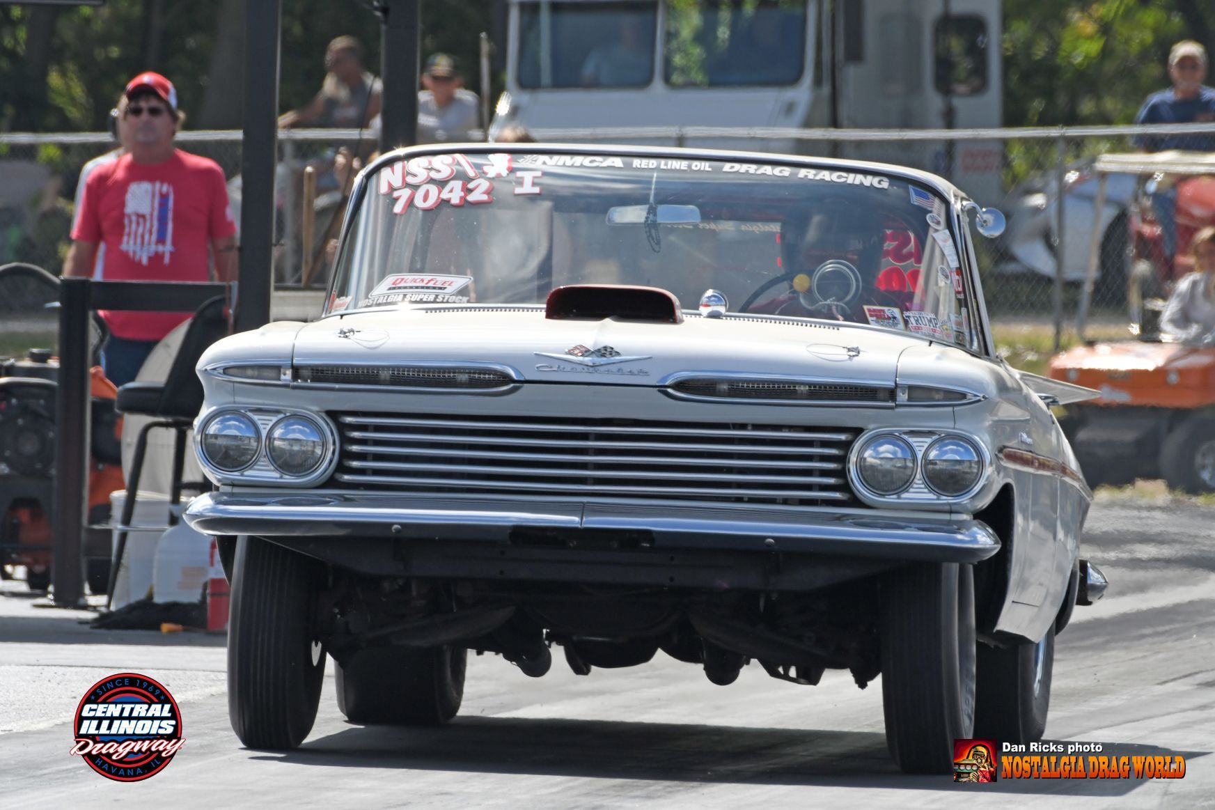 A white car is driving down a race track.