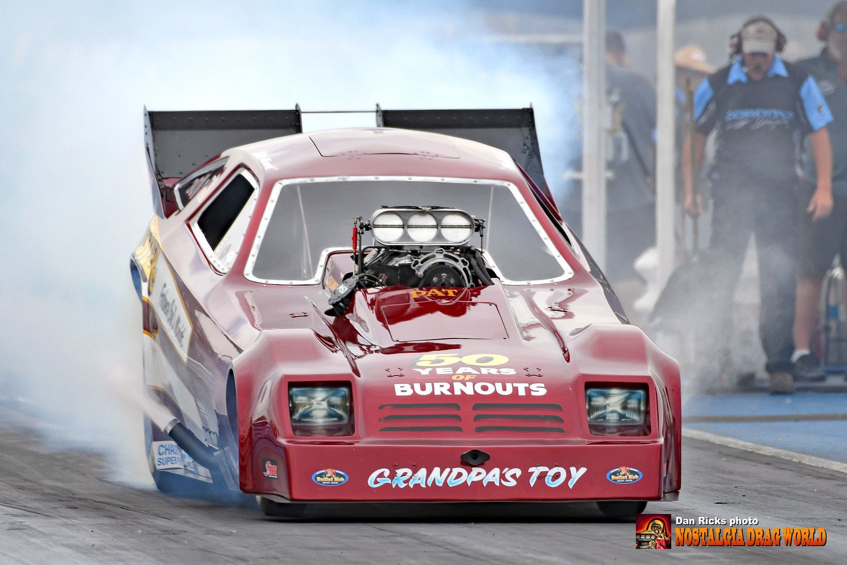 A red race car with the words grandpas toy on the front is driving down a race track.