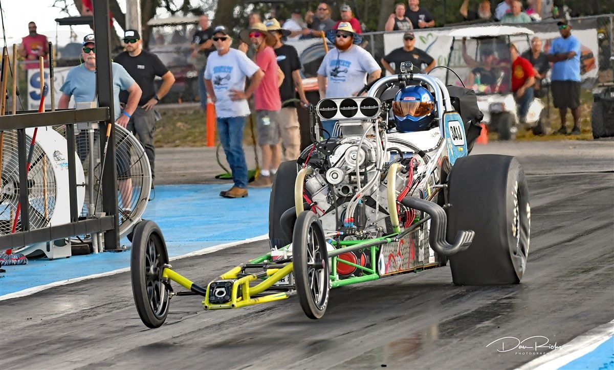 A dragster is being towed by a trailer on a race track.