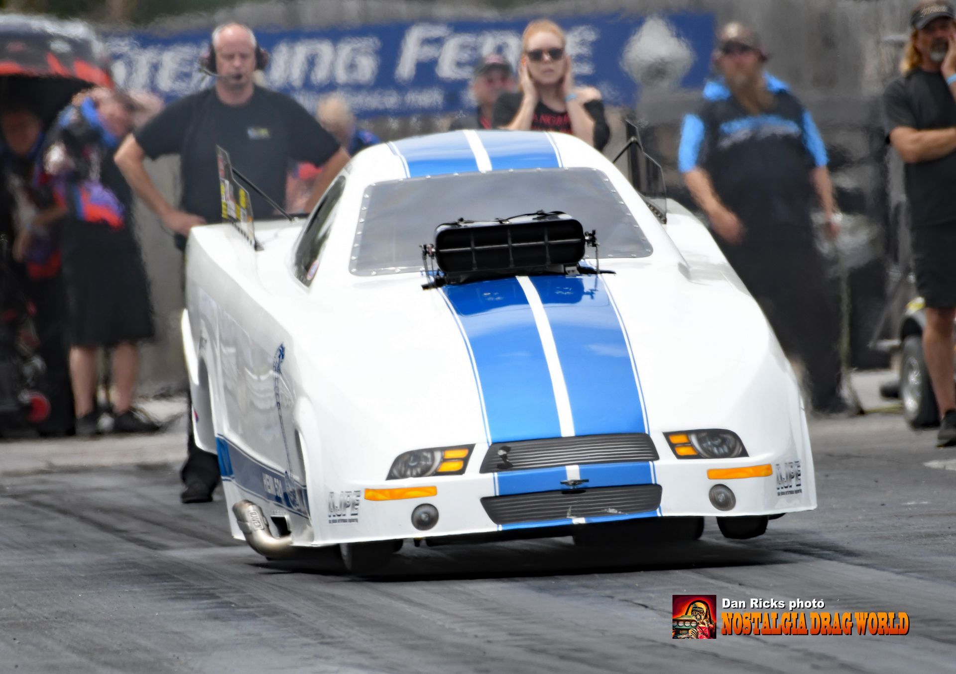 A blue and white race car is driving down a track