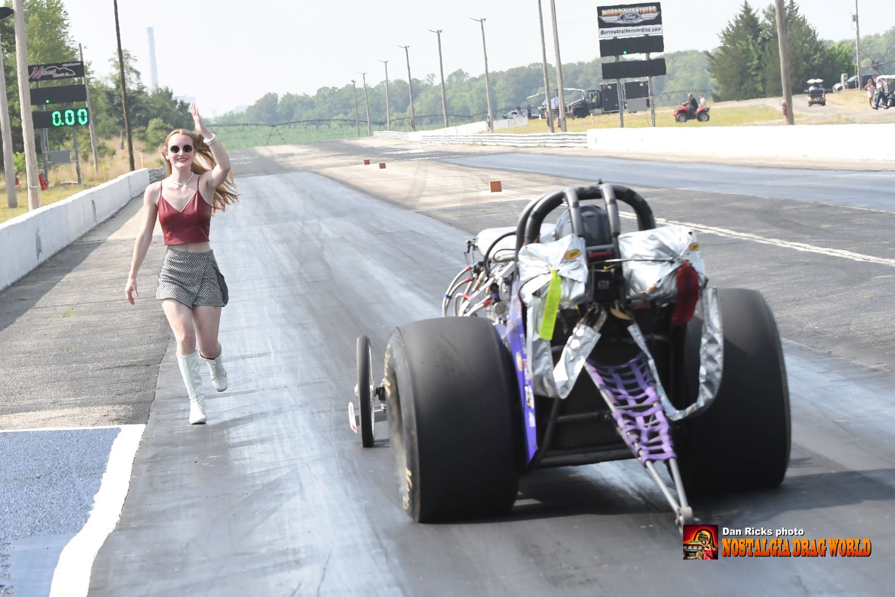 A woman is standing next to a purple race car on a track