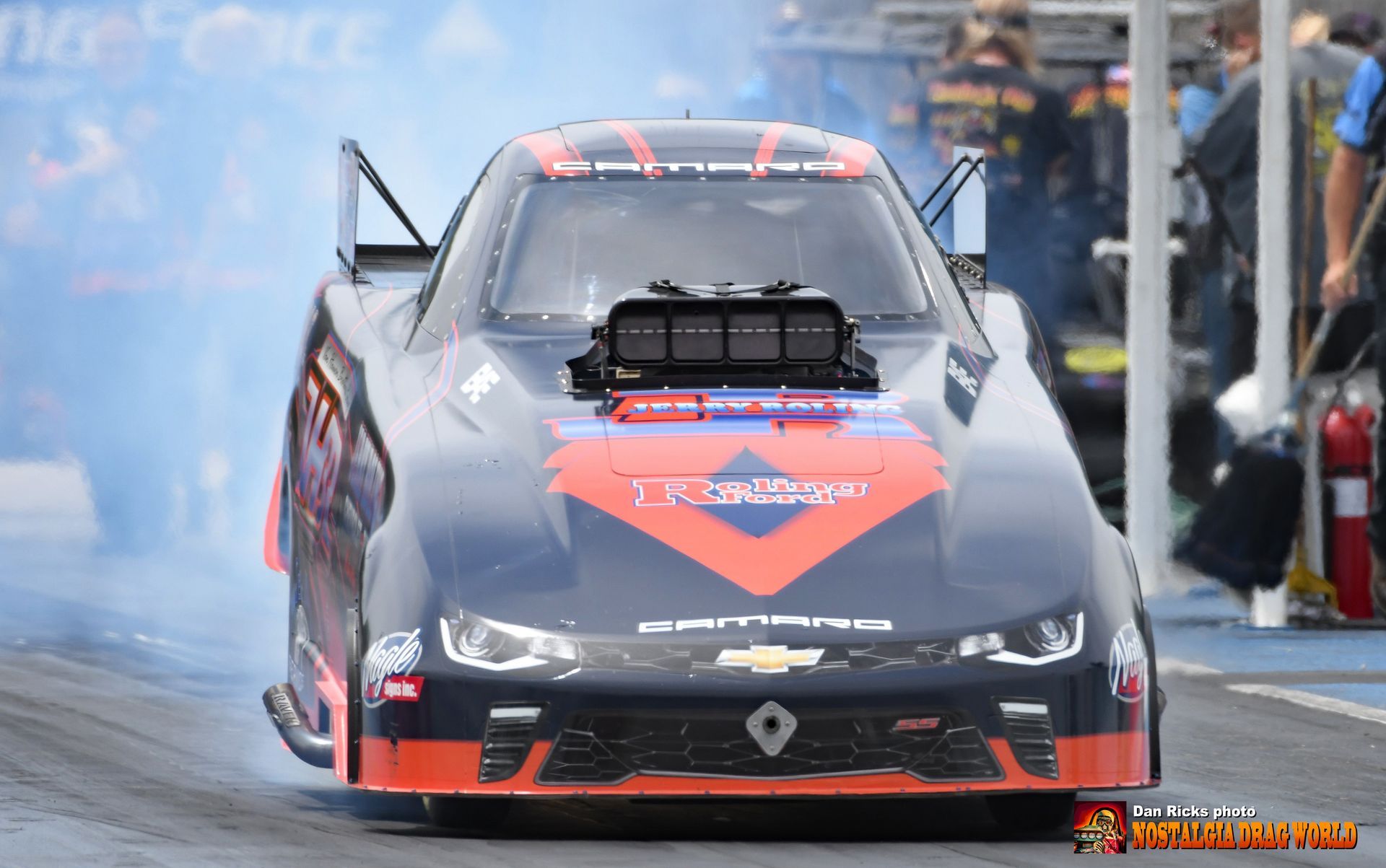 A black and orange race car is driving down a track.