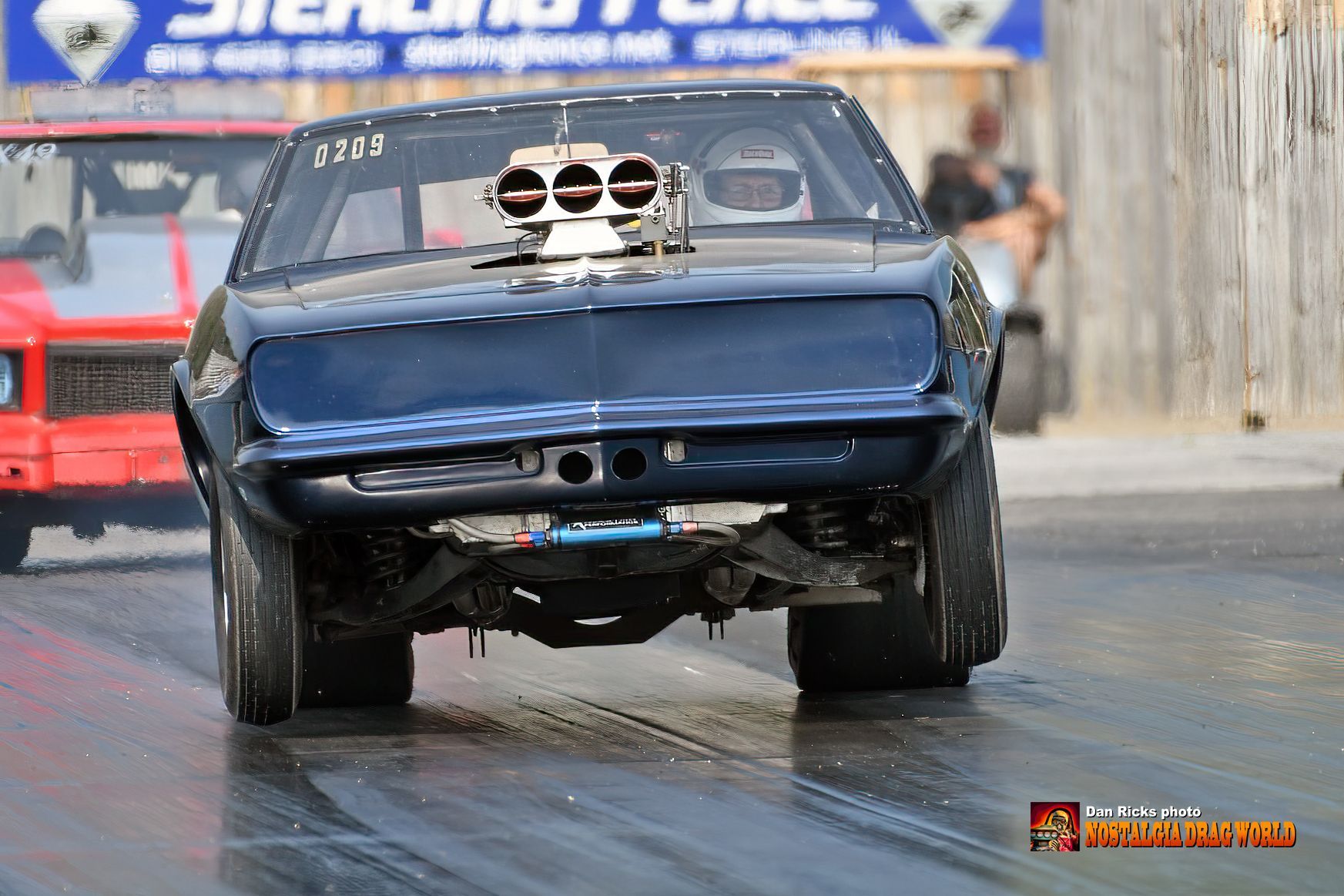 A blue car with a hood scoop is on a race track