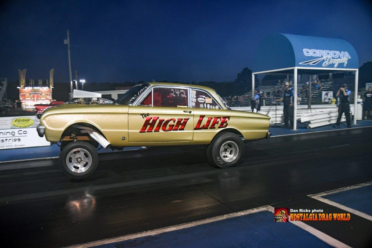 A gold car with the word high life on the side is on a race track.