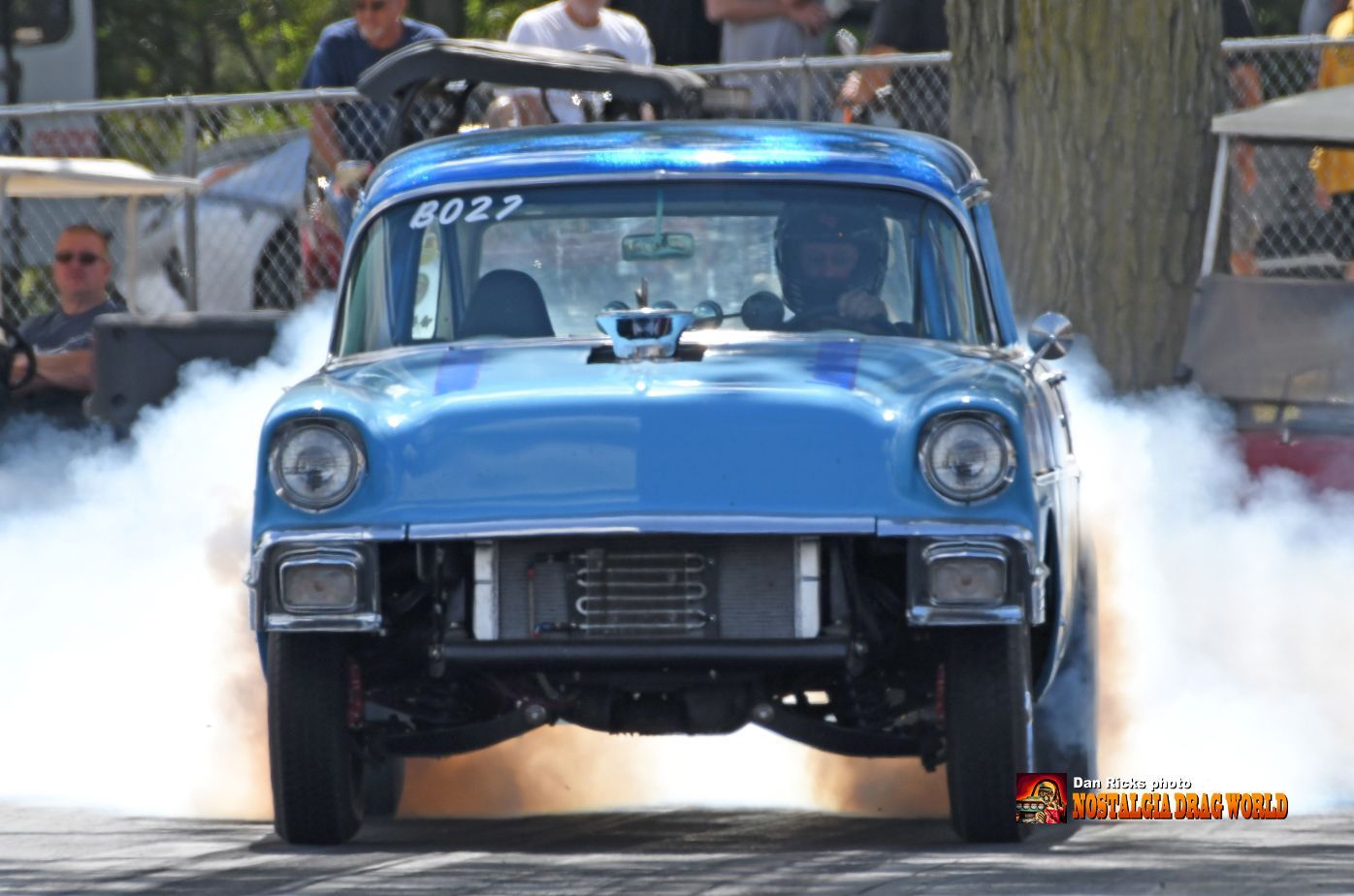 A blue car is doing a burnout on a race track.