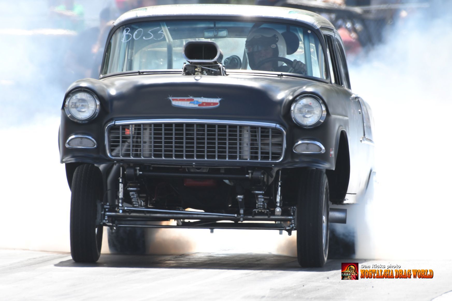 A black car is doing a burnout on a race track.