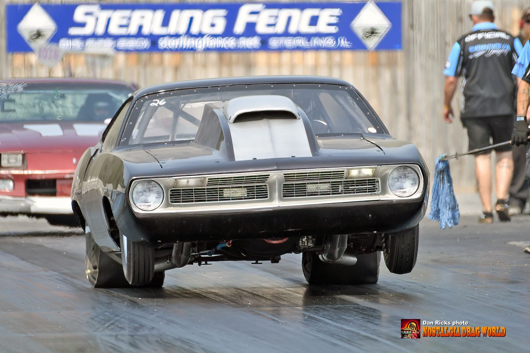 A sterling fence sign is behind a race car