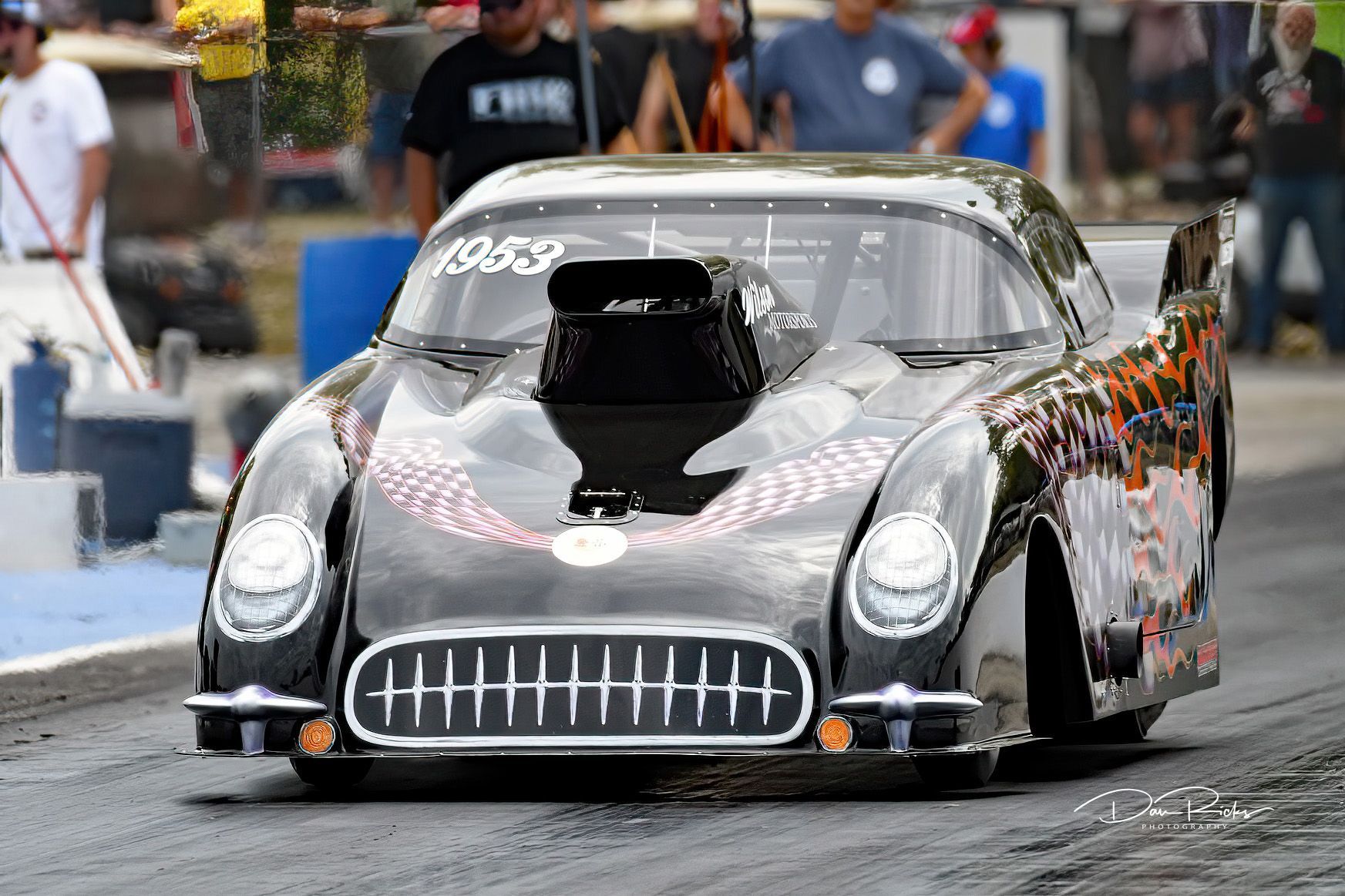 A black race car is driving down a race track.