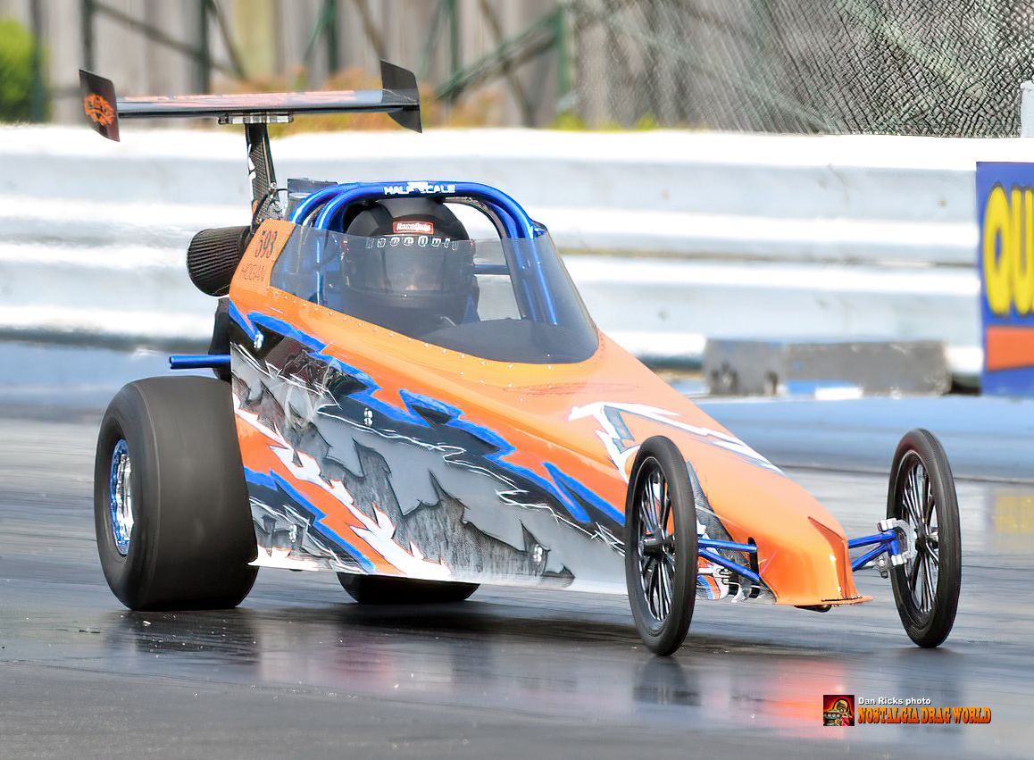 An orange and blue race car is driving down a track