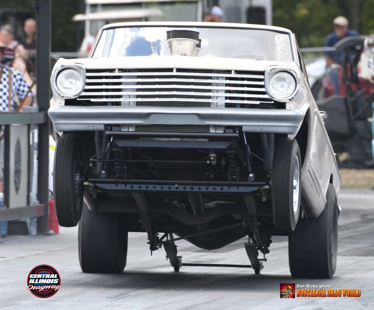 A white car is sitting on its wheels on a race track.