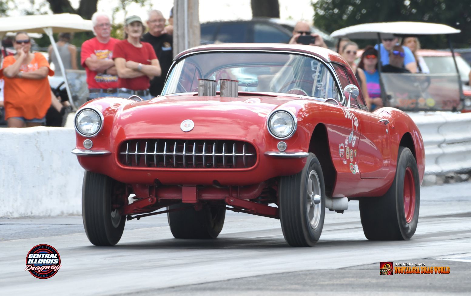 A red corvette is driving down a race track.