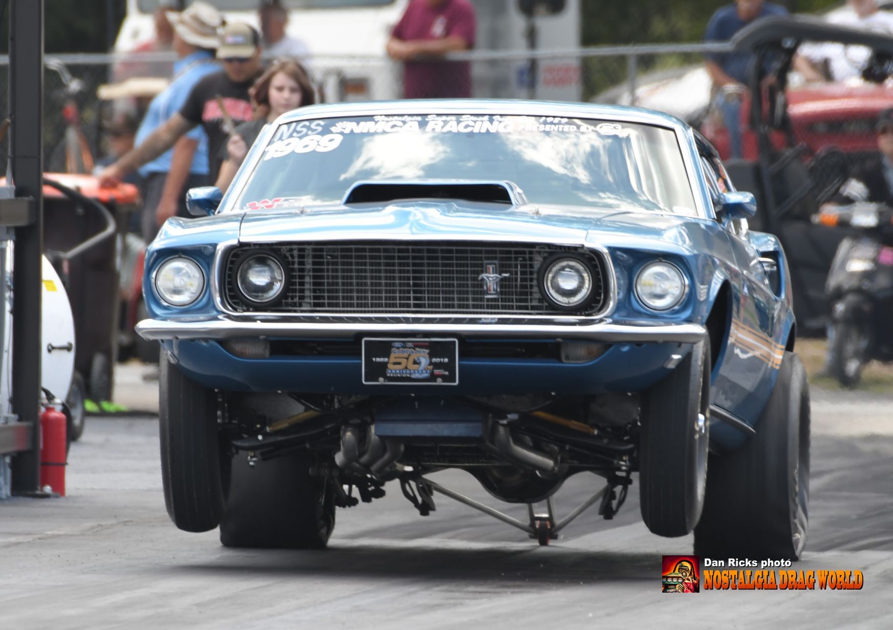 A blue mustang is driving down a race track.