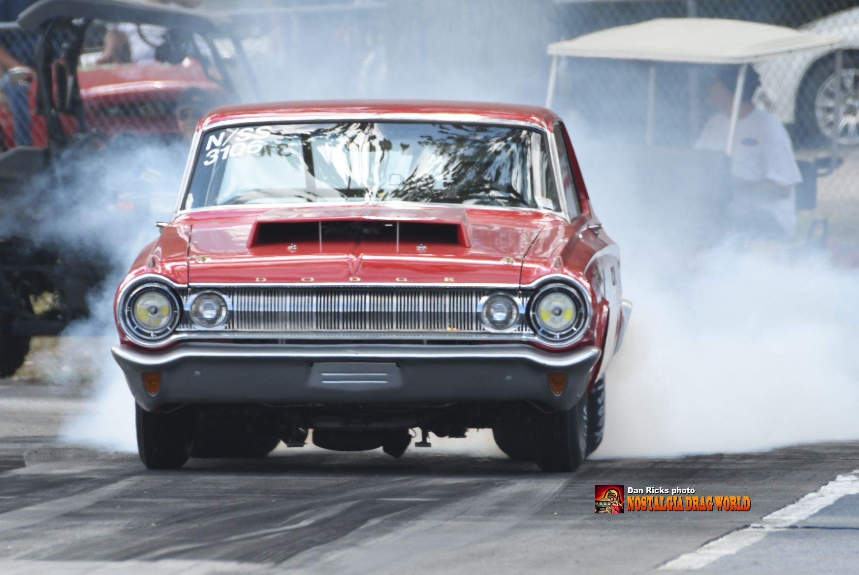 A red car is doing a burnout on a race track.