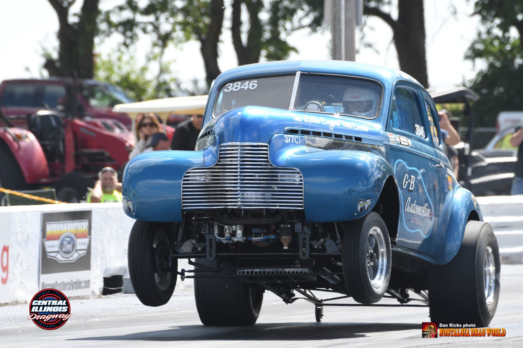 A blue car is doing a trick on a race track.