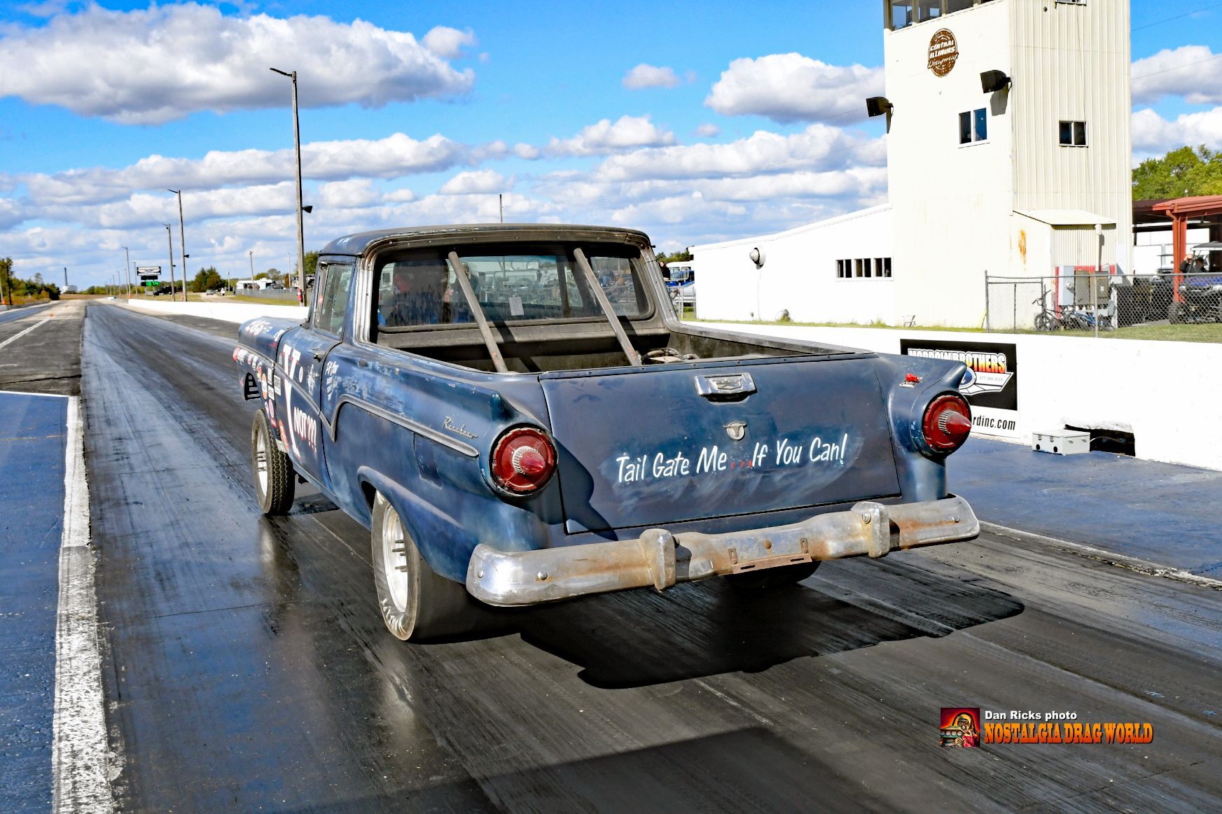 A blue truck is driving down a race track.