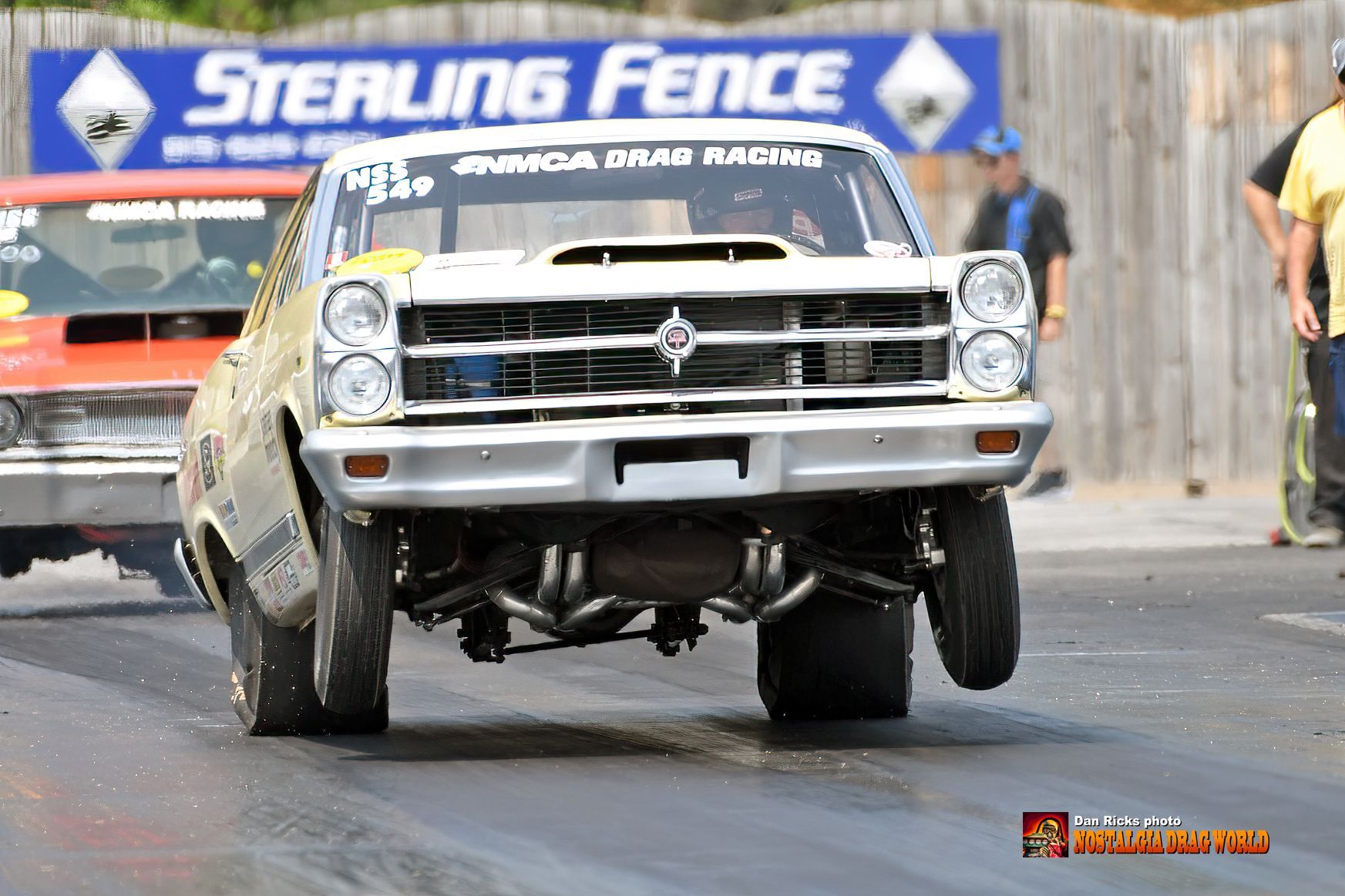 A sterling fence sign is behind a race car