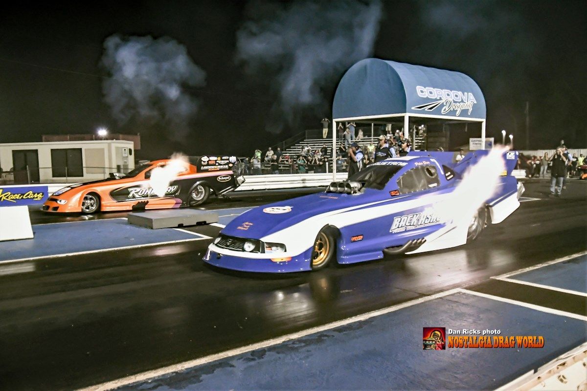 A blue and white race car is driving down a track