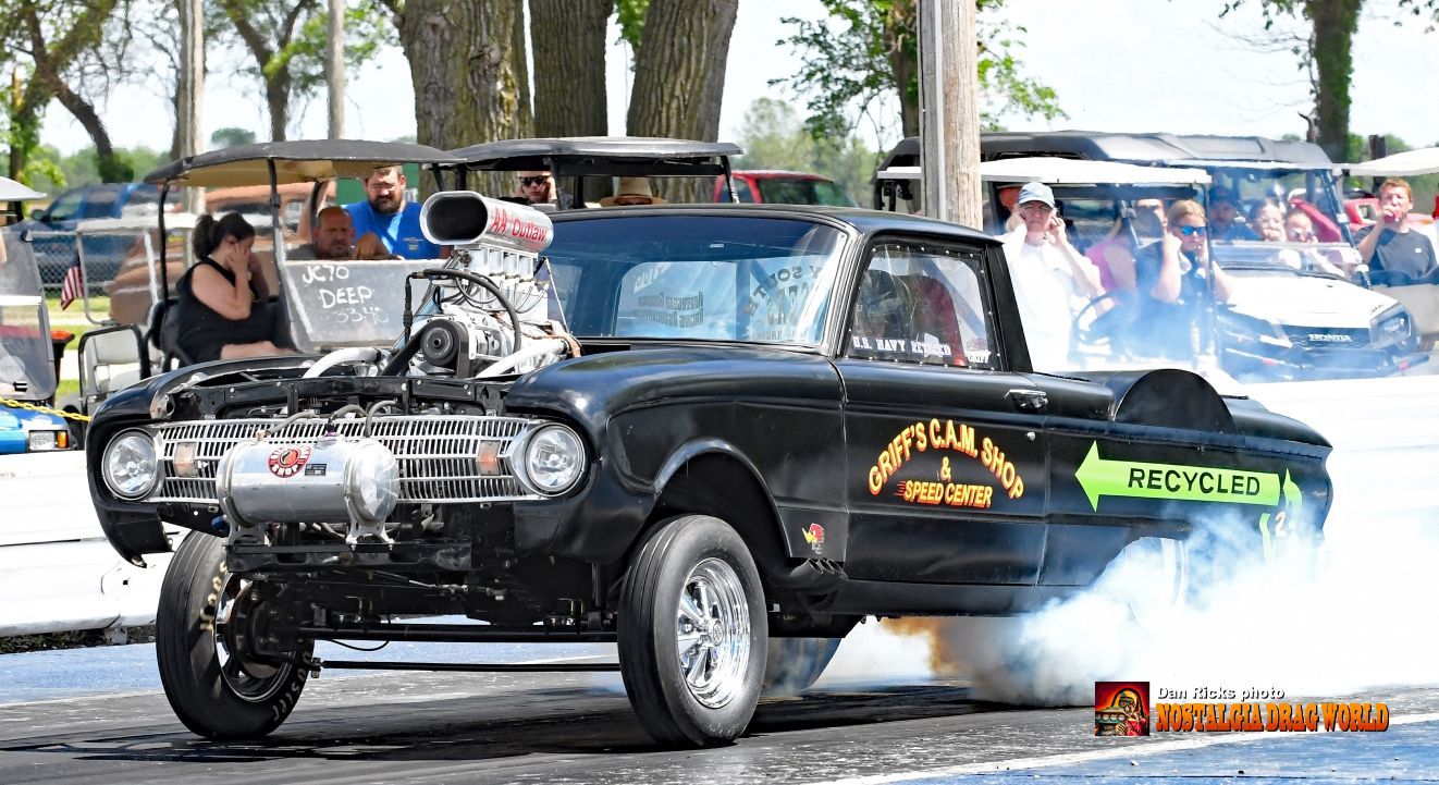 A black truck with a green arrow on the back is doing a burnout.