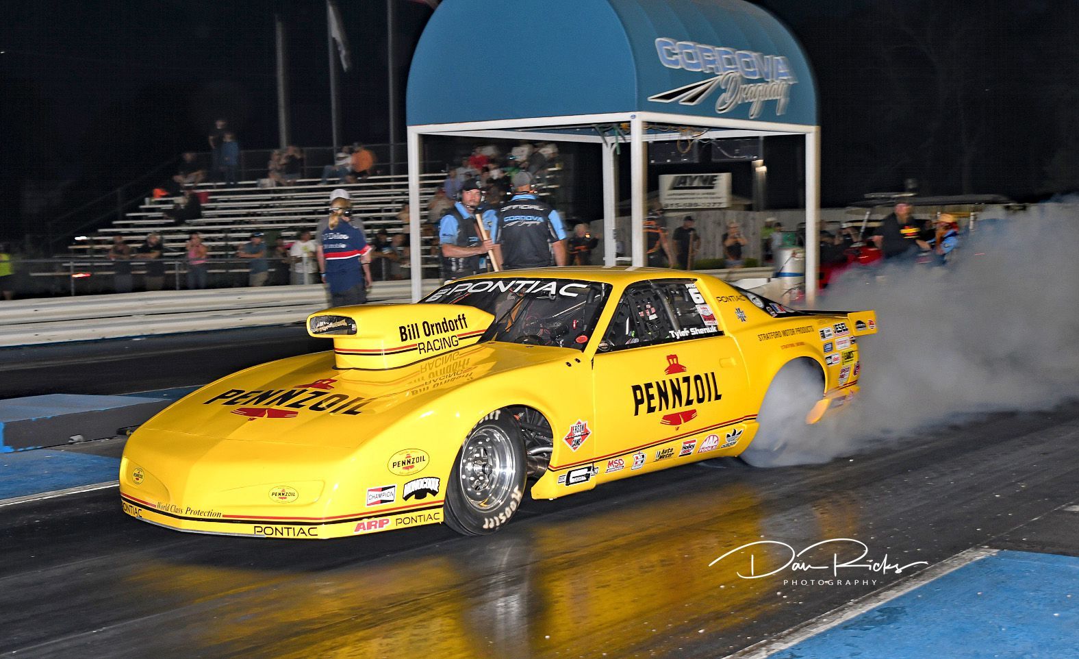A yellow race car with pennzoil written on the side