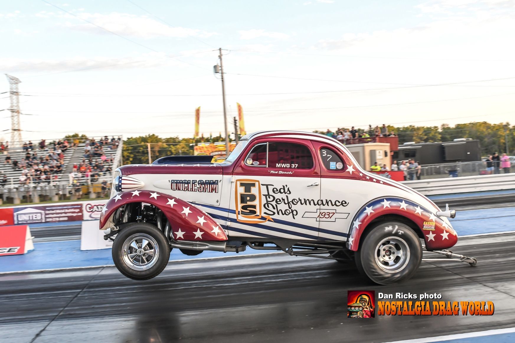 A red , white and blue car is driving down a race track.