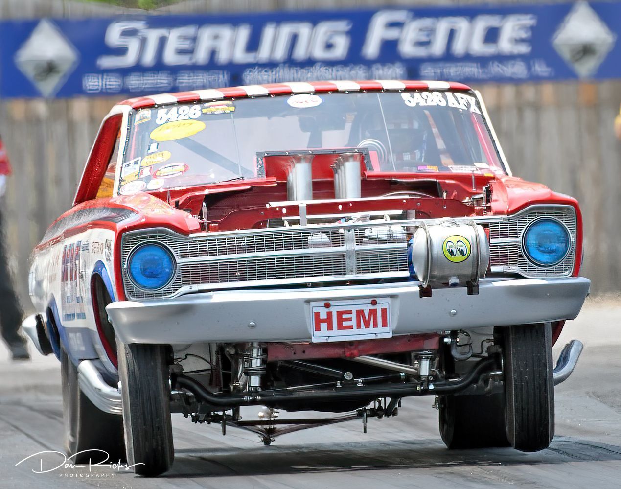A sterling fence sign is behind a race car