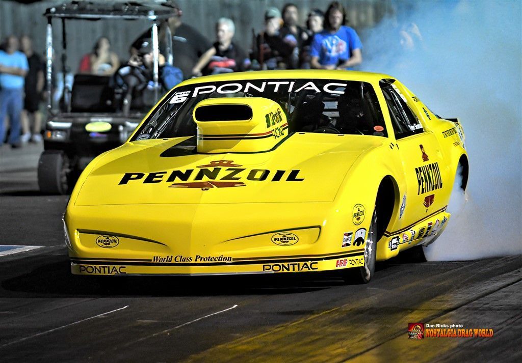 A yellow race car with pennzoil written on the side