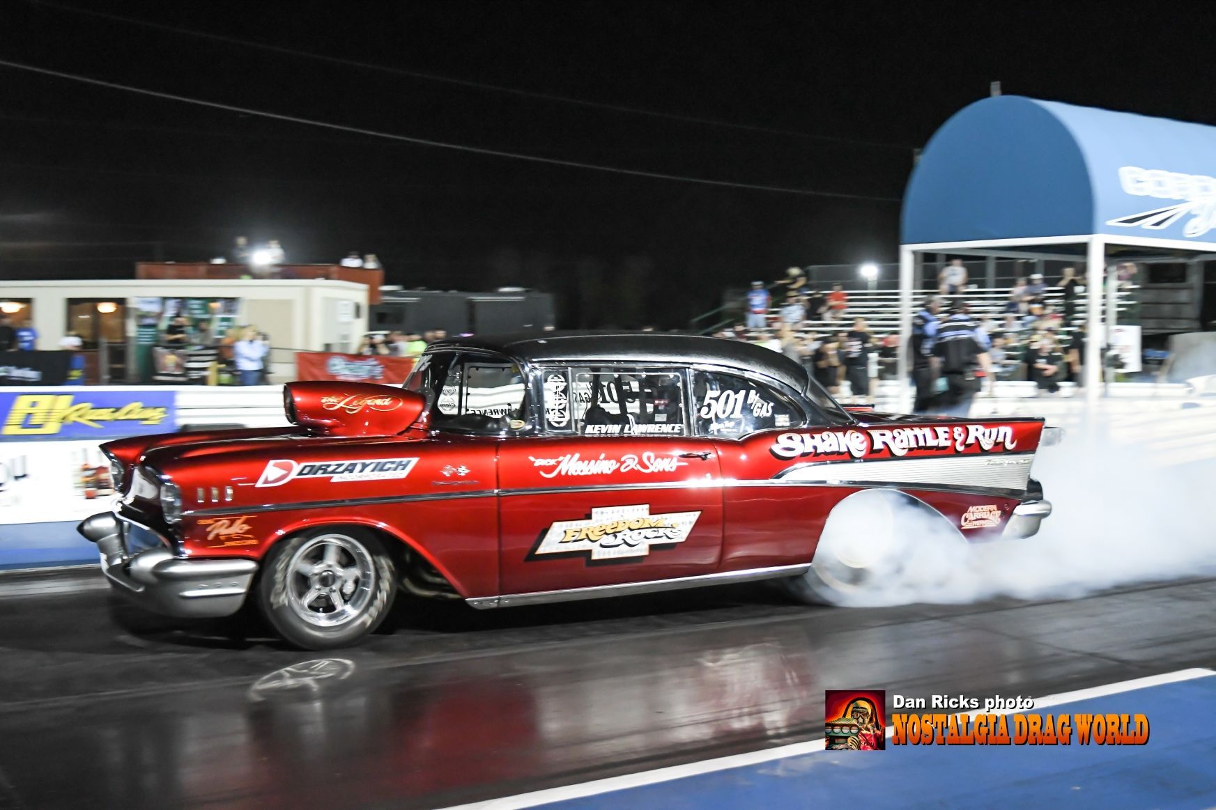 A red car is doing a burnout on a race track
