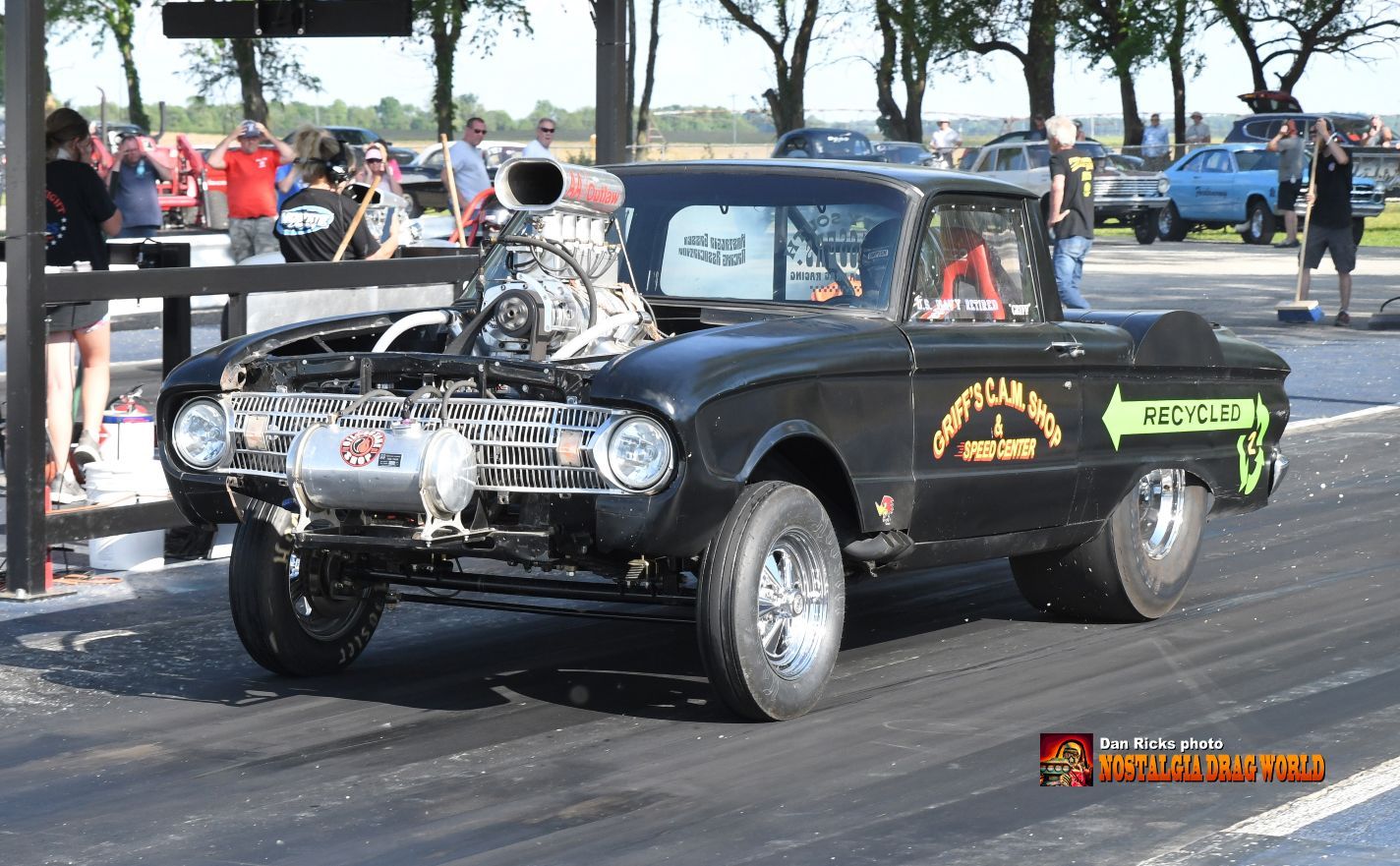 A black car with a big engine is parked on the side of the road.