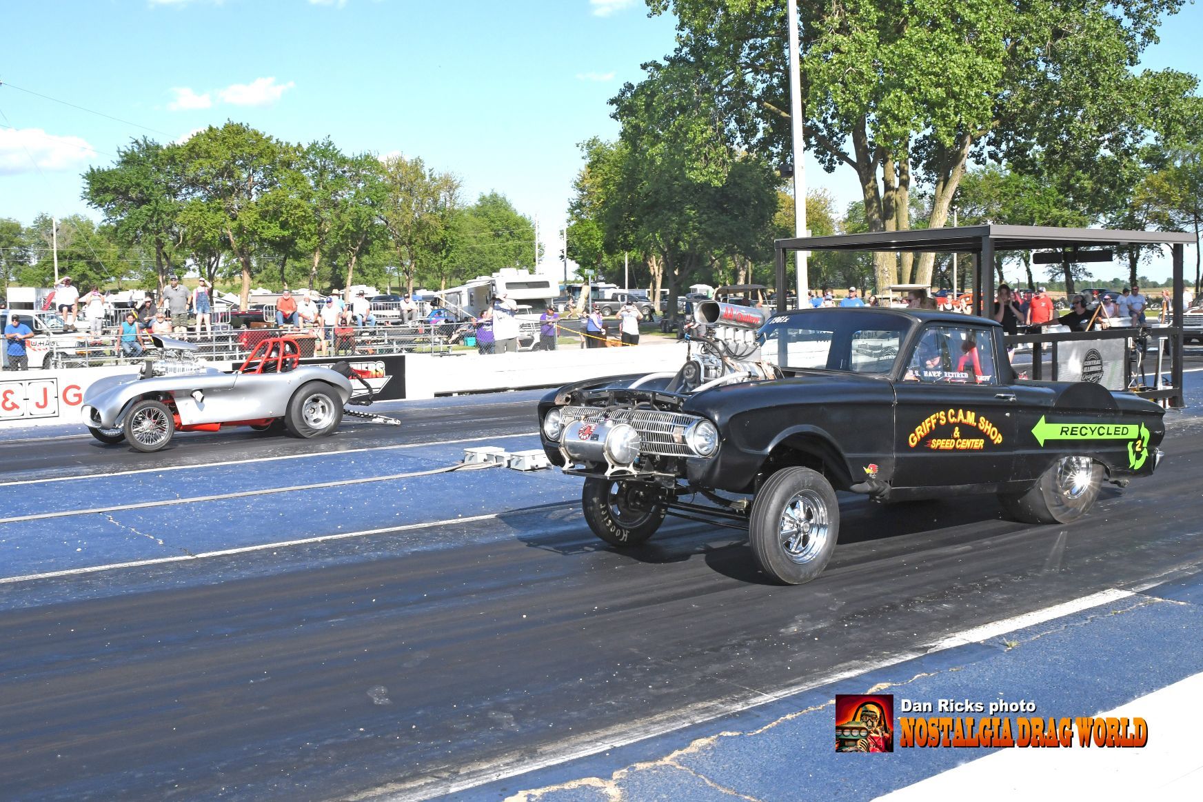 A black car with a batman logo on the side is driving down a race track