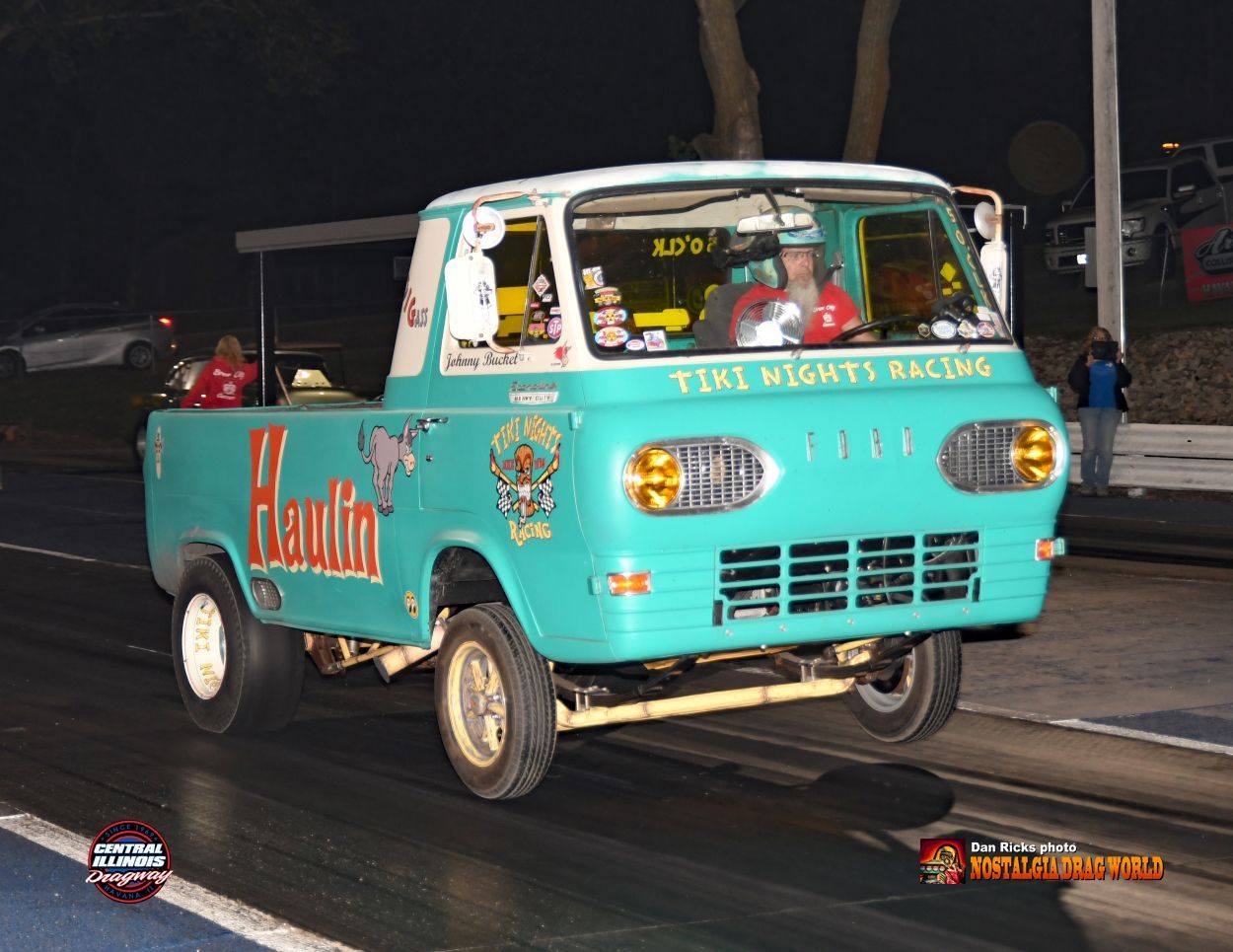 A tiki nights racing truck is driving down the road