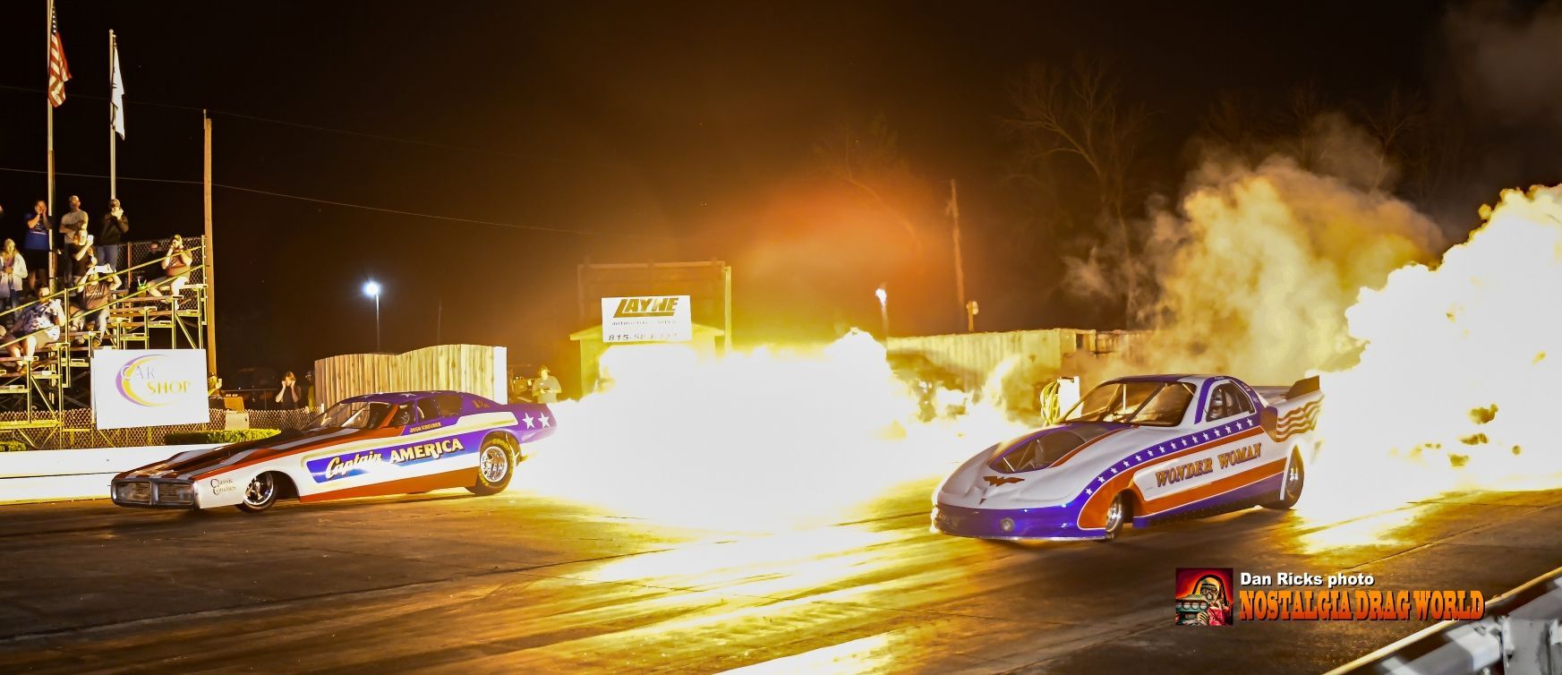 Two drag racing cars are racing on a track at night.