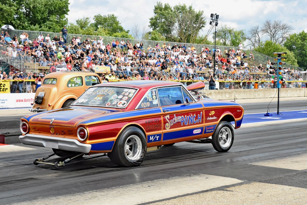 A red , blue and gold car is driving down a race track.