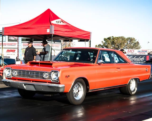 An orange car is parked in front of a red tent