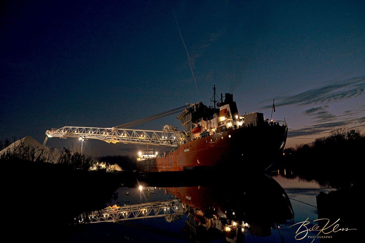 A large ship is docked in the water at night.