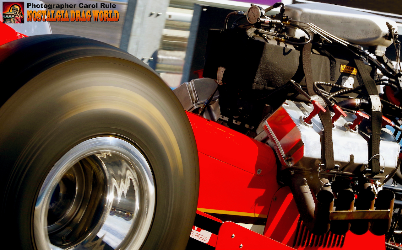 A close up of a red race car with a tire and engine