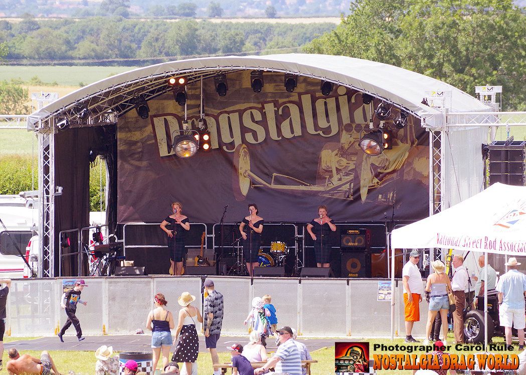 A group of people are standing in front of a stage with a large banner that says ' deustalgia ' on it