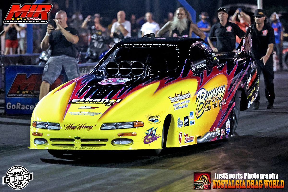 A yellow and purple drag race car is on the track