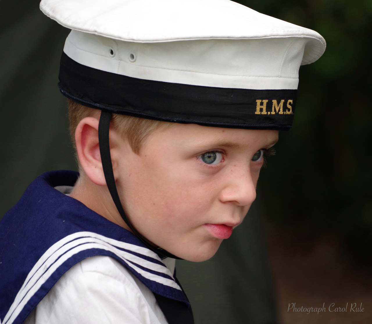 A young boy is wearing a hms hat