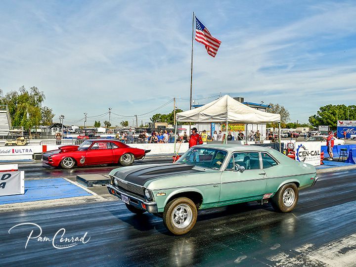 A green car is driving down a race track next to a red car.
